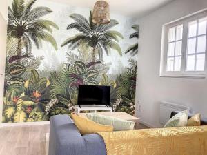 ein Wohnzimmer mit einem Wandbild von Palmen in der Unterkunft Résidence Appartements Niort wifi-parking in Niort