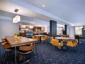 a restaurant with tables and chairs and a kitchen at Courtyard Tampa North / I-75 Fletcher in Tampa