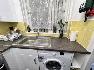 a kitchen with a sink and a washing machine at Impeccable 1-Bed Apartment in London in London