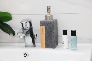 a sink with a faucet and three products on it at Brillante Appartamento di Sara -Daniele Case Vacanza in Anzio