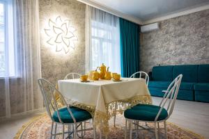 a dining room with a table with chairs and a couch at Уютная квартира-студия в старом центре города Актобе in Aktobe