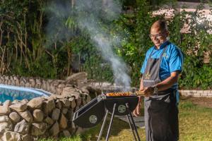 a man is cooking food on a grill at SaffronStays Chikoo Wadi- 3BDR Pet-friendly Villa with Pool in Boisar in Boisar