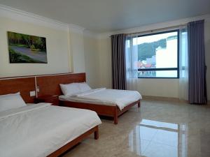 a hotel room with two beds and a window at Hotel trung hiếu in Ha Long
