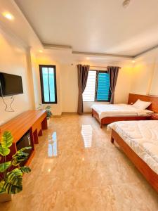 a bedroom with two beds and a flat screen tv at Hotel trung hiếu in Ha Long