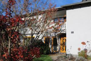 a house with a yellow door and a tree at Ferienwohnung Bliestalglück in Oberthal