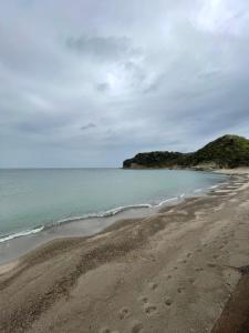 una spiaggia con impronte di piedi nella sabbia e nell'oceano di HÏSOM 湯里 a Oda