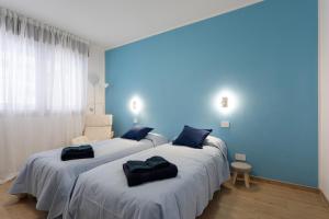two beds in a room with a blue wall at Dimora Il Parco in Bologna