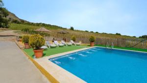 uma piscina num quintal com cadeiras e um guarda-sol em Buenavista de Illora Íllora by Ruralidays em Illora