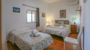 sypialnia z dwoma łóżkami i krzesłem w obiekcie Casa rural Navalonguilla Santa Olalla del Cala by Ruralidays w mieście Almadén de la Plata +27 zdjęć