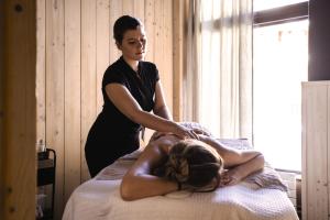 a woman sitting on a bed with a woman getting a massage at Belambra Clubs Tignes - Val Claret in Tignes