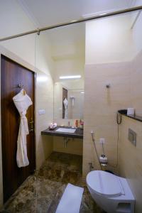 a bathroom with a toilet and a sink and a mirror at WelcomHeritage Mount Valley Resort Ranthambore in Sawāi Mādhopur