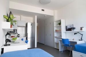 a room with a bed and a desk and a kitchen at Apartamentos Turísticos UNEATLANTICO in Santander