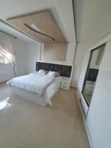 a bedroom with a large white bed and a mirror at Al Hoceima Ajdir Maroc - Maison 5 chambres 10 personnes in Al Hoceïma