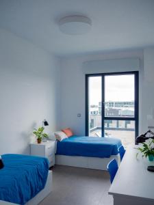 1 Schlafzimmer mit 2 Betten und einem großen Fenster in der Unterkunft Apartamentos Turísticos UNEATLANTICO in Santander