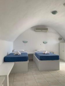 2 bedden in een witte kamer met blauwe lakens bij M.G. Hotel Studio & Apts in Perissa