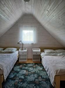 a attic bedroom with two beds and a window at Domki skowronki in Filipów