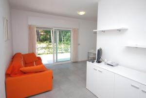 un salon avec une chaise orange et une télévision dans l'établissement Villa Liana, à Lignano Sabbiadoro