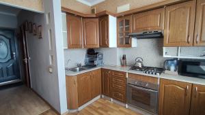 a kitchen with wooden cabinets and a stove top oven at Олександрійський бульвар 125 CityRooms in Bila Tserkva