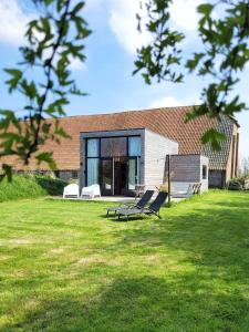 a house with two lounge chairs in a yard at NEW! Tiny House Lantliv Oostkapelle, bij de boer in Oostkapelle