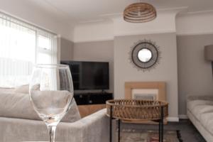 sala de estar con sofá y copa de vino en Cosy 3Bed Bungalow in West Kirby, Free Parking en Frankby