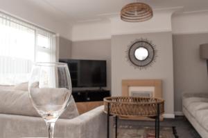a living room with a couch and a wine glass at Cosy 3Bed Bungalow in West Kirby, Free Parking in Frankby