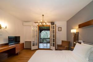 a bedroom with a bed and a tv and a chair at Hotel Munsch Restaurant & Wellness, Colmar Nord - Haut-Koenigsbourg in Saint-Hippolyte +87 photos