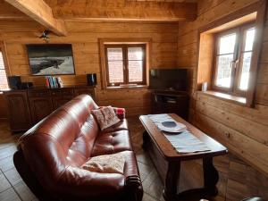 a living room with a leather couch and a table at Chata Wetłyna II in Wetlina