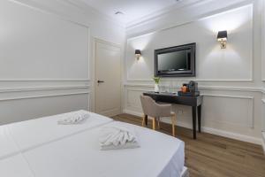 a bedroom with two beds and a desk and a television at Belle Boutique in Sliema