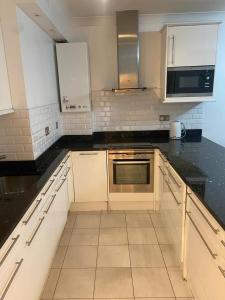 a kitchen with white cabinets and a black counter top at Cozy two bedroom flat in the heart of London in London