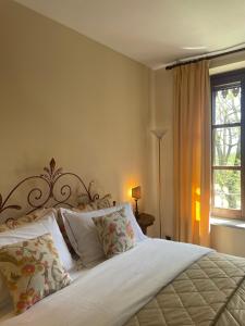a bedroom with a white bed with pillows and a window at Dimora Storica La Corte Delle 4 Stagioni in Ozzano Monferrato