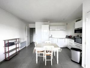 - une cuisine blanche avec une table et des chaises dans l'établissement Spacieux T2 + Parking à 5 min d'Aix, à Aix-en-Provence