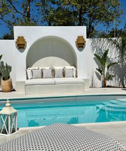 a white couch sits next to a swimming pool at Byblos Mare-The Exclusive Beach Front Villa in Skala Sotiros