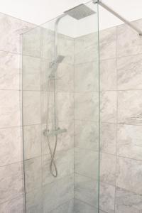 a shower with a glass door in a bathroom at Cosy 3Bed Bungalow in West Kirby, Free Parking in Frankby
