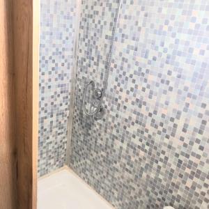 eine Dusche mit blauen und grauen Fliesen im Bad in der Unterkunft לנפוש על גלגלים in Kefar H̱ananya