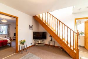 a living room with a staircase and a television at Oak Tree Cottage - Pendle - Forest of Bowland in Burnley