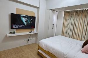 a bedroom with a bed and a flat screen tv at Steff's Condo 211 At Centrio in Cagayan de Oro