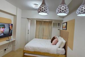 um quarto com uma cama, uma televisão e luzes pendentes em Steff's Condo 211 At Centrio em Cagayan de Oro