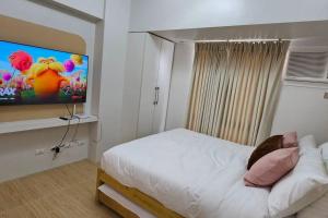 um quarto com uma cama branca e uma televisão de ecrã plano em Steff's Condo 211 At Centrio em Cagayan de Oro