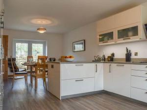 een keuken met witte kasten en een tafel met stoelen bij Oak Tree Cottage - Pendle - Forest of Bowland in Burnley