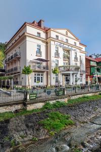 a large white building next to a river at Małopolanka & Spa in Krynica Zdrój