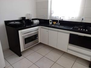 a kitchen with white cabinets and a black counter top at Sua casa na praia em Cabo Frio in São Pedro da Aldeia