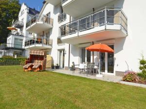 una casa con sombrilla naranja y césped en Residenz Falkenberg - Apt. 03, en Ostseebad Sellin