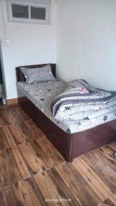 uma cama num quarto com piso em madeira em Darjeeling Homestay Nyano Ghar em Darjeeling