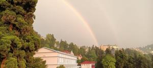 ein Regenbogen am Himmel über einer Stadt mit Bäumen in der Unterkunft Darjeeling Homestay Nyano Ghar in Darjeeling