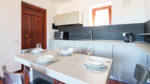 una cocina con una mesa con platos y copas de vino en Welcomely - Petra - Residence Country di Porto Rotondo, en Porto Rotondo