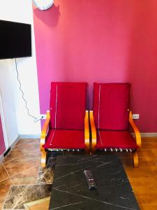 two red chairs in a room with a pink wall at Nights bucharest apartment oldtown in Bucharest