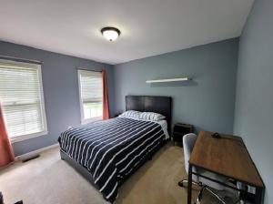 a bedroom with a bed and a desk and two windows at Hetten Manor in Woodbridge