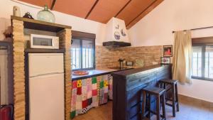 una cucina con frigorifero e bancone con sgabelli di La Marchoza Aznalcázar by Ruralidays ad Aznalcázar