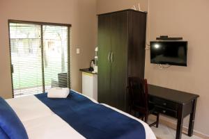 a bedroom with a bed and a desk and a television at Rip van Winkel Guest House in Lephalale