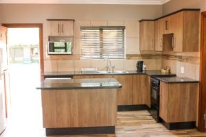 a kitchen with wooden cabinets and a black counter top at Rip van Winkel Guest House in Lephalale